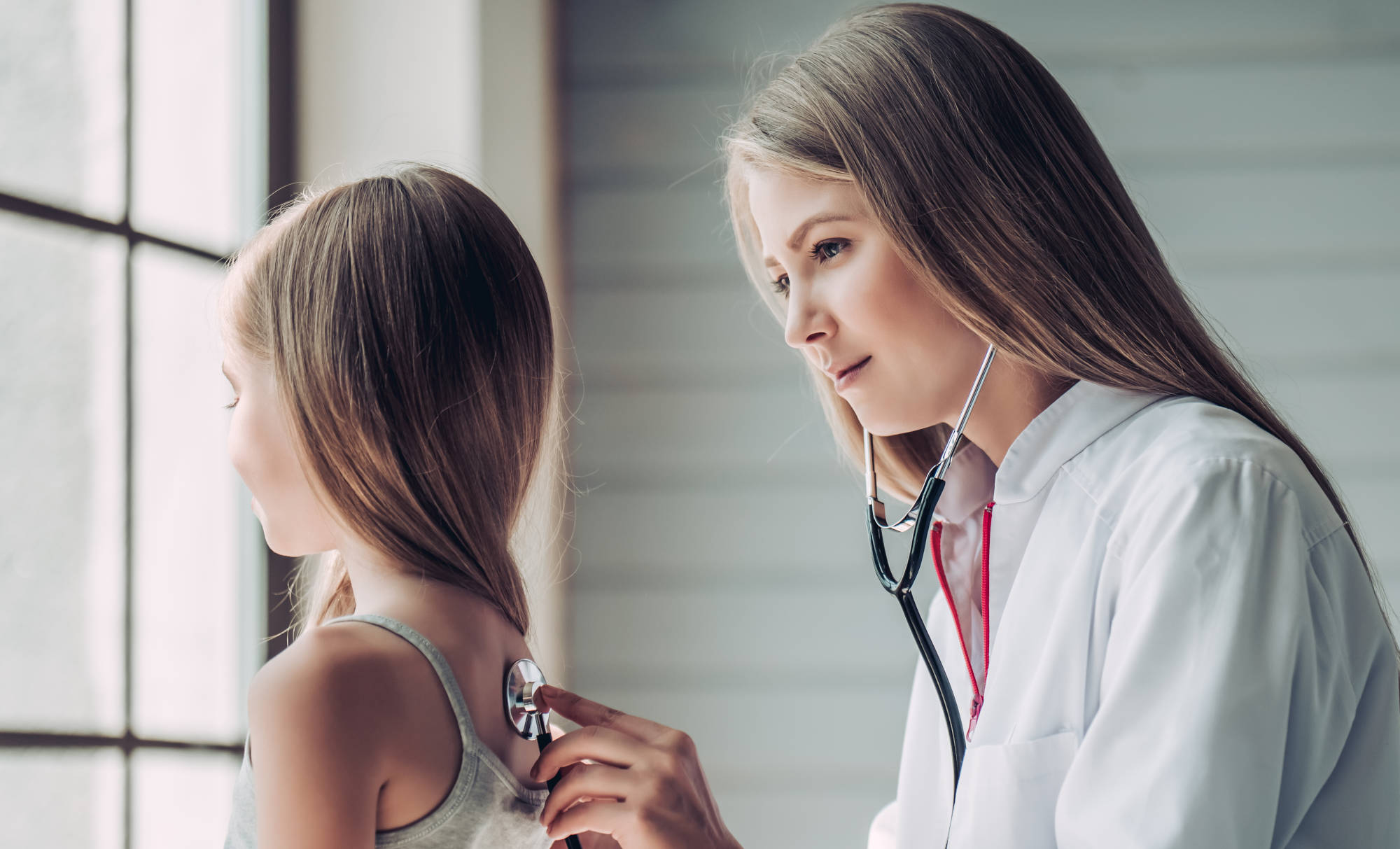 Female pediatrician listening to child's back