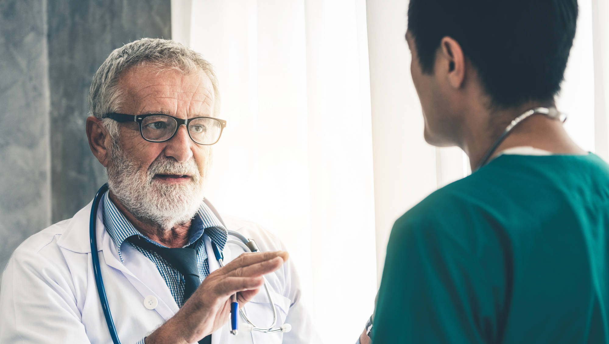 Older male doctor talking to younger doc